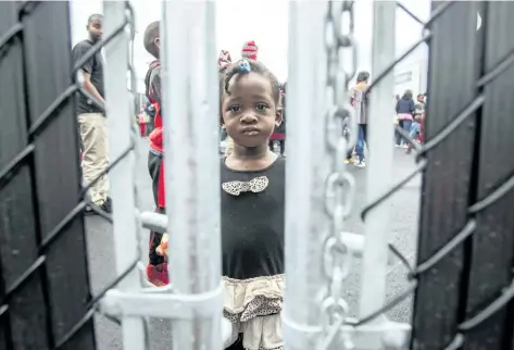  ?? GEOFF ROBINS/AFP/GETTY IMAGES ?? This photo taken on Aug. 5 shows a girl who crossed the Canada/U.S. border illegally with her family, claiming refugee status in Canada, as she looks through a fence at a temporary detention centre in Blackpool, Que. Niagara is expecting an influx of Haitian refugees in wake of the U.S. government announcing that it may revoke their protected status there.