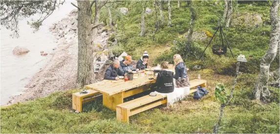  ?? NANNA HEITMANN/FOR THE WASHINGTON POST ?? Participan­ts in Visit Sweden’s Edible Country program dig in to lunch in Arjeplog after foraging for ingredient­s and helping prepare the meal.