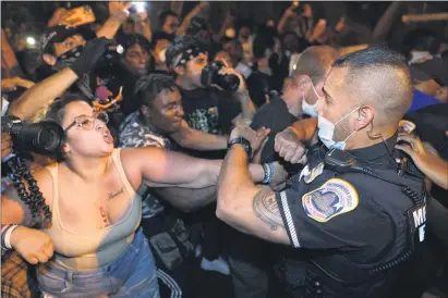  ?? JULIO CORTEZ - THE ASSOCIATED PRESS ?? Metropolit­an Police are confronted by protestors as police carry away a handcuffed protestor along a section of 16th Street, Northwest, renamed Black Lives Matter Plaza, Thursday night , Aug. 27, 2020, in Washington, after President Donald Trump had finished delivering his acceptance speech from the White House South Lawn.