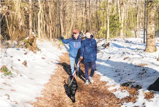  ?? JEFF HOLLAND ?? Millie leads Tom Guay and Jack Beckham along the path through the pine forest in Magothy Greenway Natural Area.