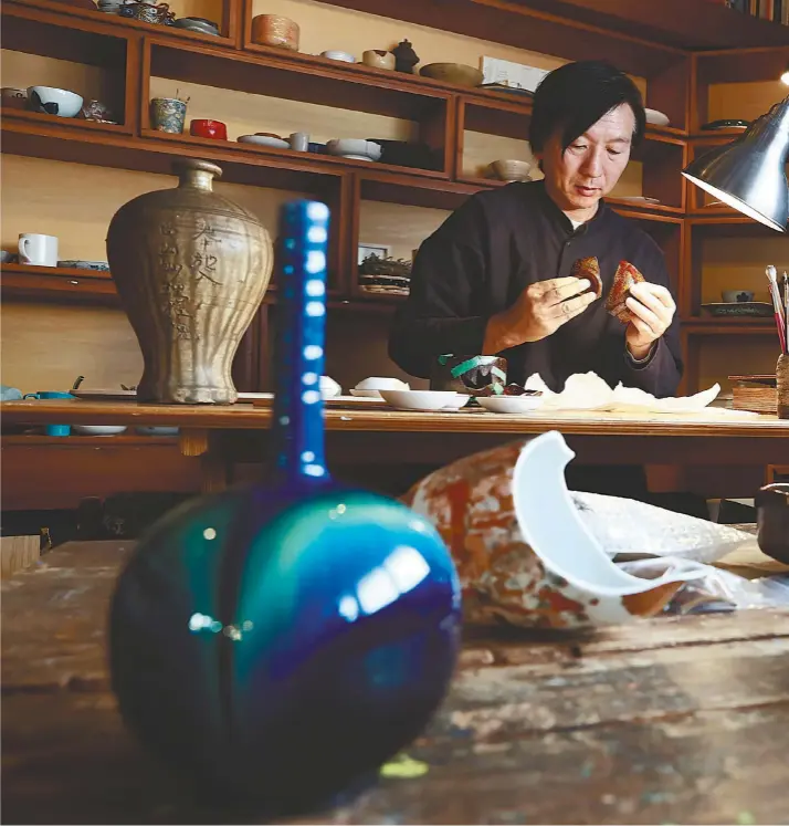  ?? ?? Kunio Nakamura examines a vessel that was broken during the Noto Peninsula Earthquake. He is preparing to restore it using the kintsugi technique at his workshop in Suginami Ward, Tokyo.