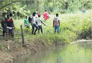  ?? FILE ?? Curious onlookers gather along the banks of the Martha Brae River after Jace Jones and Llewellyn Reid drowned last month.