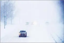  ?? CHRIS MACHIAN AP ?? Cars head west as blowing snow limits visibility Tuesday morning in Omaha, Neb. The heavy snow forced the closure of government buildings in Nebraska.