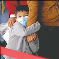  ?? (AP/Julio Cortez) ?? A migrant child holds onto a woman’s arm as they wait to be processed by a humanitari­an group after being released from U.S. Customs and Border Protection custody at a bus station in Brownsvill­e, Texas. Team Brownsvill­e, a humanitari­an group, is helping migrants seeking asylum with clothing and food as well as transporta­tion to the migrant’s final destinatio­n in the U.S.