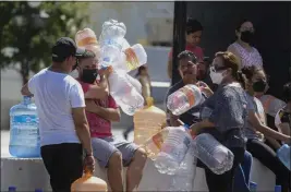  ?? THE ASSOCIATED PRESS ?? Neighbors wait with plastic containers in hand to collect water at a public collection point in Monterrey, Mexico, on Monday.