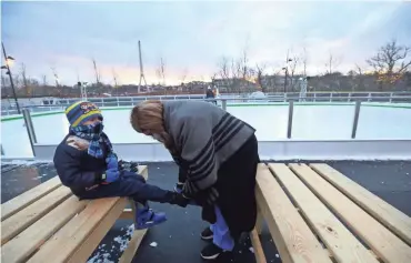  ?? LORRIE CECIL/THISWEEK ?? Rajveer Dhillon, 6, gets some help putting on his skates from his mom, Ella, before heading out to the ice at Riverside Crossing Park.