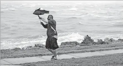  ?? [ERIC GAY/THE ASSOCIATED PRESS] ?? Matt Looingvill struggles with his umbrella as he tries to walk in the wind and rain on Friday in Corpus Christi.