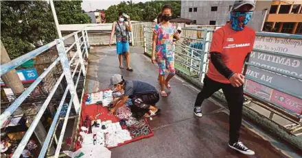  ?? EPA PIC ?? People walking past a vendor arranging products on a pedestrian crossing bridge in Quezon City, Metro Manila, recently. The Philippine­s has recorded 35 cases of the Delta variant of Covid-19.