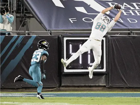  ?? PHELAN M. EBENHACK AP ?? Tight end Mike Gesicki makes a leaping catch in front of Jaguars cornerback C.J. Henderson for a 15-yard touchdown in the first half, one of two TD passes thrown by Ryan Fitzpatric­k.