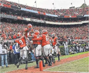  ?? DALE ZANINE/USA TODAY SPORTS ?? Georgia celebrates a TD by Elijah Holyfield (13) that helped the Bulldogs rout Georgia Tech. Georgia plays Alabama for the SEC title.