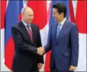  ?? SPUTNIK, KREMLIN PHOTO VIA AP ?? Japanese Prime Minister Shinzo Abe and Russian President Vladimir Putin shake hands Monday prior to the Eastern Economic Forum in Vladivosto­k, Russia.