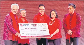  ?? ?? Foo (left) presenting one of the donations from SME Sabah to SMJK Shan Tao, while Joachim (second left) and Phoong (centre) look on