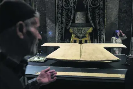  ?? Ozan Kose / AFP ?? People look at the cloak of Prophet Mohammed that is on display at the Hirka-I-Serif mosque in Istanbul.