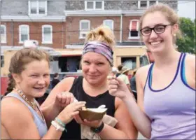  ?? JESI YOST — FOR MEDIANEWS GROUP ?? Teagan Tyson, 11, Jaime Tyson, and Ashley Schmoll, 17, share Poutine (fries with beef gravy with goat cheese) from Gourmand Food Truck during the Boyertown Museum of Historic Vehicles fifth annual The Truck Stops Here- Mobile Madness food truck festival on June 29.