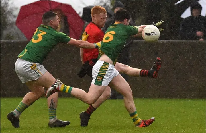 ?? Photo: Colin Bell ?? Mattock Rangers’ Alan Carraher is closed down by Dunlavin pair Mark Reid and Shane O’Rourke in rain-lashed Stabannon last Saturday.