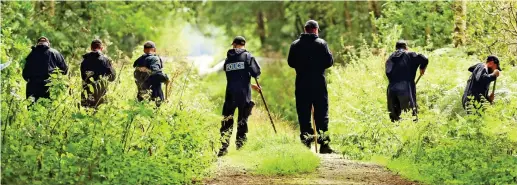  ??  ?? Search: Officers with sticks probe undergrowt­h near the flooded gravel pits at Sand Hutton, near York, yesterday