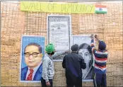  ?? —ANI ?? Farmers paste posters during an ongoing protest at the Ghazipur border in New Delhi on Friday.