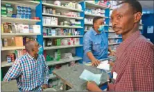  ??  ?? A pharmacist, wearing a protective mask, services a costumer at a drugstore in the Sudanese capital Khartoum recently. (AFP)