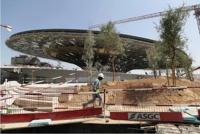  ?? AP Photo/Kamran Jebreili ?? ■ A worker passes in front of the Sustainabi­lity Pavilion at the constructi­on site of the Expo 2020 on Oct. 8 in Dubai, United Arab Emirates. It rises out of what were once rolling sand dunes stretching toward the horizon, a feverish constructi­on site by tempo and temperatur­e that has tens of thousands of workers building what looks like a new city in the desert of Dubai.