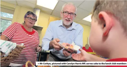  ??  ?? > Mr Corbyn, pictured with Carolyn Harris MP, serves cake to the lunch club members