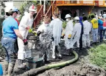  ?? Lorraine Hjalte/calgary Herald ?? Volunteers are coming to High River by the thousands, including Leigh Evans, left, and Steve Bond, who held up the end of a mud bucket brigade for a home on 5th Avenue and 1st Avenue S.E.