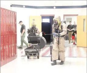  ?? LYNN KUTTER ENTERPRISE-LEADER ?? Two members of the 61st Civil Support Team enter Farmington Middle School for a training exercise to determine if a vial of unknown liquid is dangerous.