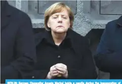  ??  ?? BERLIN: German Chancellor Angela Merkel holds a candle during the inaugurati­on of the memorial for the victims of last year’s deadly truck attack at the Christmas market at Breitschei­dplatz in Berlin.—AFP