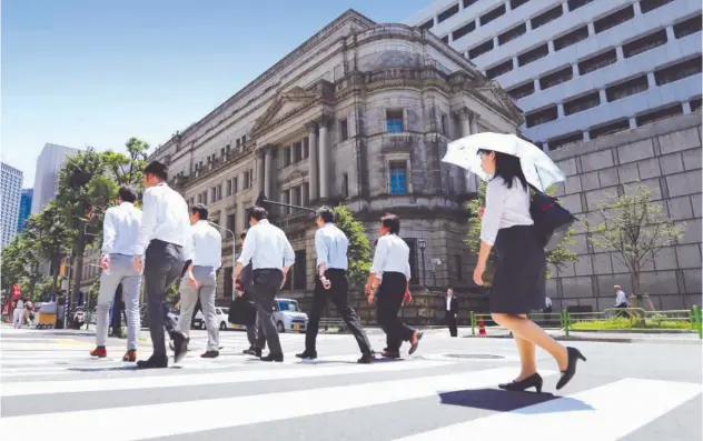  ?? Reuters ?? ↑ People walk past the Bank of Japan building in Tokyo, Japan.