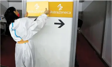  ?? The Associated Press ?? Q In this Sunday file photo a medical worker wearing protective gear sets up boards with the names of the vaccines at a vaccinatio­n center in Belgrade, Serbia. Results from a U.S. trial of AstraZenec­a’s COVID-19 vaccine may have used “outdated informatio­n,” U.S. federal health officials said early Tuesday.