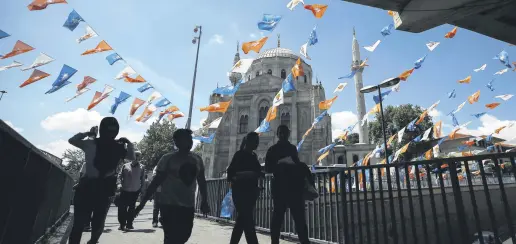  ??  ?? People walk under Justice and Developmen­t Party (AK Party) flags, Istanbul, June 20.