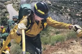  ??  ?? MACKENZIE JENNINGS, 27, a single mother who works as a waitress near Lake Hughes, gets a hand up during a mock firefighti­ng drill at the camp.