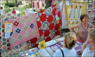  ?? Photo courtesy Shiloh Museum ?? Lynda Hicklin chats in front of her quilt display during the Ozark Quilt Fair in September 2010. In 1995 the Arts Center of the Ozarks handed over the sponsorshi­p and operation of the fair to the museum. Held on the lawn under an ancient burr oak tree, the fair features colorful quilts, old and new, hanging from clotheslin­es.