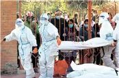  ??  ?? Female soldiers wearing personal protective equipment (PPE) lift a stretcher with the body of a coronaviru­s victim in Kathmandu, Nepal