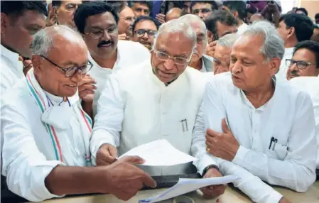  ?? ?? MALLIKARJU­N KHARGE , flanked by Digvijay Singh and Ashok Gehlot, files his nomination papers for the post of party president at the AICC headquarte­rs in New Delhi on September 30.