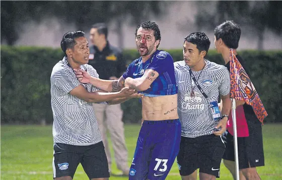  ??  ?? Chonburi’s Thiago Cunha, centre, is restrained by his team’s staff members during the incident.