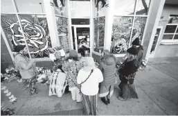  ?? DAVID ZALUBOWSKI/AP ?? Mourners gather Tuesday outside a tattoo shop, one of the scenes of Monday’s attacks. Three people were gunned down in Denver and two in suburban Lakewood.