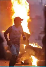  ?? AFP ?? BAGHDAD: Iraqi demonstrat­ors run next to a burning tyre during a demonstrat­ion against state corruption, failing public services and unemployme­nt on Oct 5, 2019. —