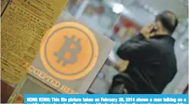  ?? — AFP ?? HONG KONG: This file picture taken on February 28, 2014 shows a man talking on a mobile phone in a shop displaying a bitcoin sign during the opening ceremony of the first bitcoin retail shop in Hong Kong.