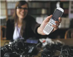  ?? Chris Walker / Chicago Tribune 2015 ?? Nicole Finzer, digital curation librarian at Northweste­rn University, holds a Toshiba flip phone that belonged to the late actress Karen Black, an alumna.