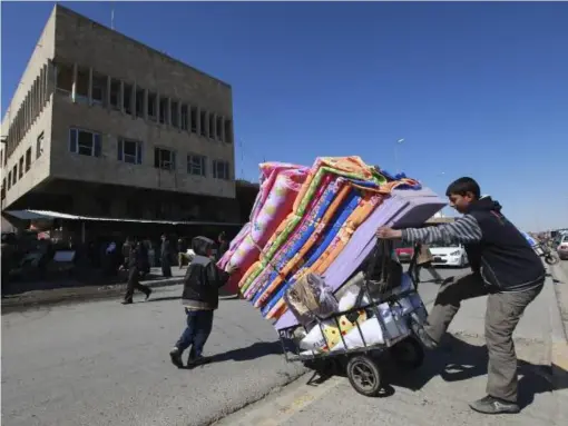  ?? (Reuters) ?? A boy transfers mattresses on a cart in Mosul