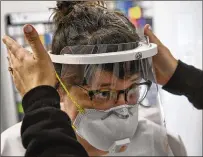  ?? TONI L. SANDYS / WASHINGTON POST ?? Tracy McCormick tests a prototype of a protective face shield at Hatch Exhibits in Elkridge, Md. After furloughin­g all 23 employees, the owners realized they could use their machinery to make protective gowns and face shields for health care workers and bring back employees.