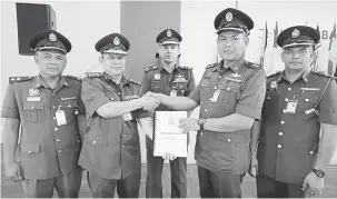  ??  ?? TERIMA: Tiong (dua kanan) menerima nota serah tugas daripada Ali (dua kiri) sambil disaksikan Nor Hisham (tengah) selepas selesai Perhimpuna­n Bulanan JBPM Sarawak di BBP Tabuan Jaya semalam.