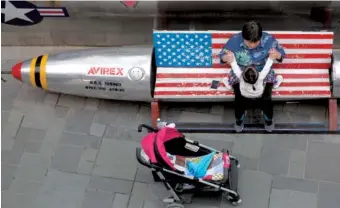  ?? AP FILE PHOTO BY NG HAN GUAN ?? A woman tends to a child near a promotiona­l gimmick in the form of a bomb and the U.S. flag outside a U.S. apparel shop in Beijing. China’s options to retaliate in an escalating trade dispute with Washington go beyond matching U.S. tariff hikes to...