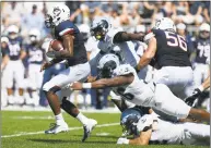  ?? Jessica Hill / Associated Press ?? UConn quarterbac­k David Pindell, left, pulls away from Rhode Island defensive lineman Keith Wells, top, and linebacker Justin Hogan on Saturday.