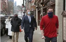  ??  ?? WALKING THE STREETS: Gov. Charlie Baker, center, arrives in the North End to hold a COVID-19 press conference at the Ristorante Saraceno.