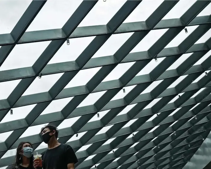  ??  ?? A couple wearing face masks to help curb the spread of the coronaviru­s walk by a structure of a shopping mall in Beijing, Sunday, June 6, 2021. Photo: AP