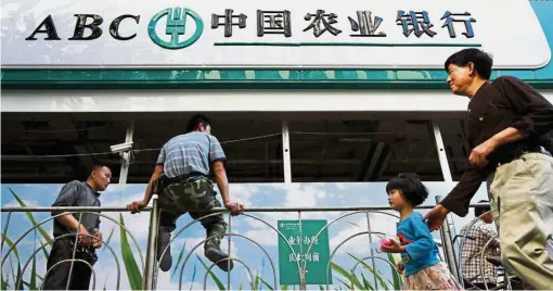  ?? — Reuters ?? Money boost: A file photo of people walking past a branch of Agricultur­al Bank of China in Shanghai. Authoritie­s are trying to up lending to SMEs.