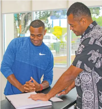  ?? Photo: Fiji Sports Council. ?? Pacific sprint king Banuve Tabakaucor­o, left, checks out the booking list at the Fiji Sports Council office in Suva.