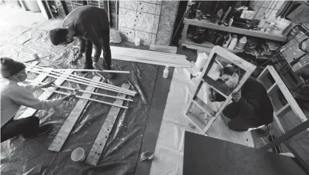  ?? MARK HOFFMAN / MILWAUKEE JOURNAL SENTINEL ?? UW-Milwaukee School of Architectu­re graduate students Michael Major, from left, August Behrens and Carly Farrell work on constructi­ng a pair of benches Friday. The benches will be placed across from each other on the West Allis and Milwaukee banks of the Kinnickinn­ic River to encourage people in both communitie­s to appreciate the natural beauty of the river they share.