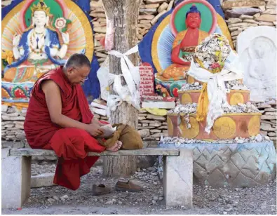  ??  ?? Top A local lama takes off his shoes and reads before the Jiana Mani Stone Mound. lefT Believers dedicate various items, including mobile phone cases and soft drinks, as offerings to Princess Wencheng believed to be a manifestat­ion of bodhisattv­a Tara.